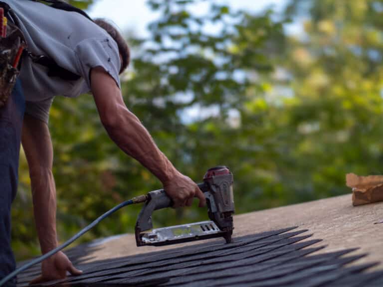 Worker using nail gun on roof